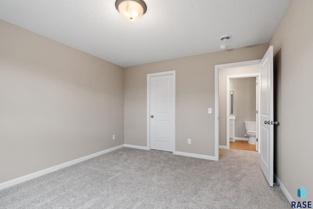 unfurnished bedroom with light colored carpet and a textured ceiling