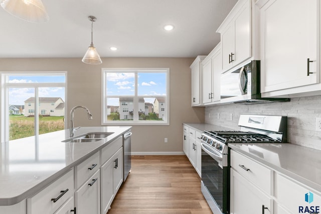 kitchen with a wealth of natural light, white cabinetry, light hardwood / wood-style flooring, and appliances with stainless steel finishes