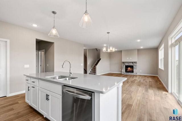 kitchen with sink, decorative light fixtures, a center island with sink, dishwasher, and white cabinetry