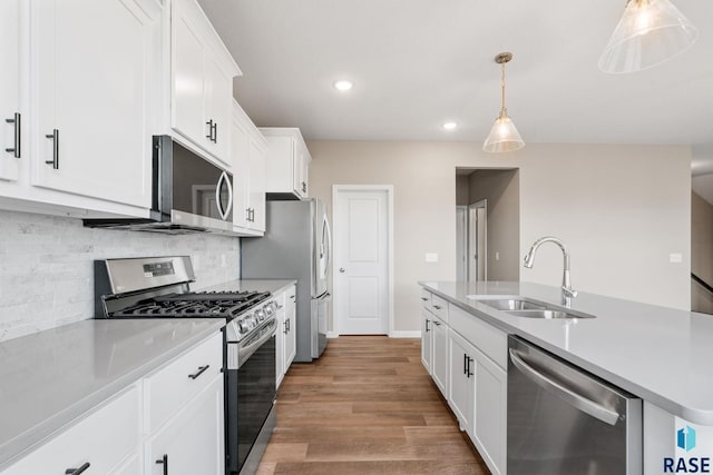 kitchen featuring white cabinetry, sink, stainless steel appliances, light hardwood / wood-style flooring, and pendant lighting