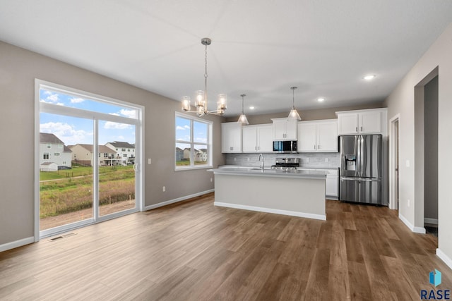 kitchen with dark hardwood / wood-style floors, white cabinetry, stainless steel appliances, and decorative light fixtures