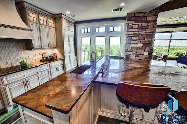 kitchen with decorative columns, premium range hood, plenty of natural light, and sink