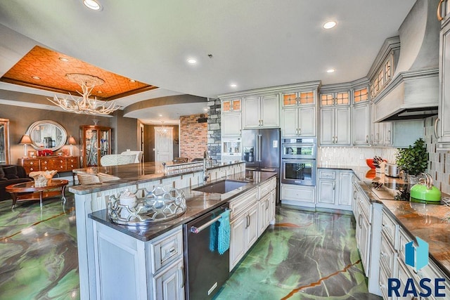 kitchen featuring custom exhaust hood, stainless steel appliances, sink, pendant lighting, and a large island with sink