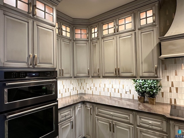 kitchen featuring tasteful backsplash, dark stone countertops, gray cabinetry, and appliances with stainless steel finishes