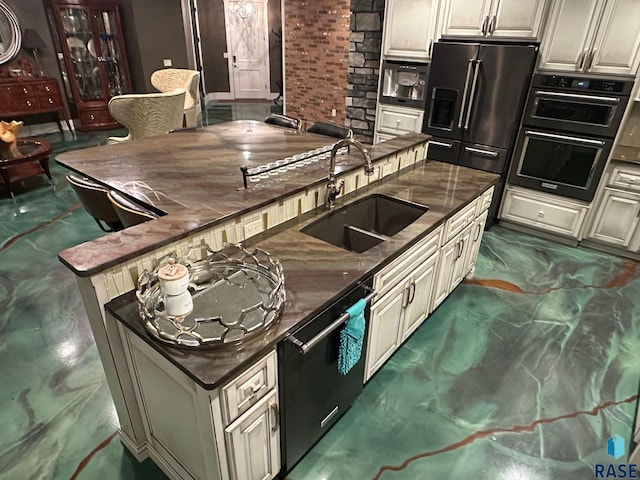 kitchen with sink, black dishwasher, brick wall, stainless steel refrigerator with ice dispenser, and cream cabinets