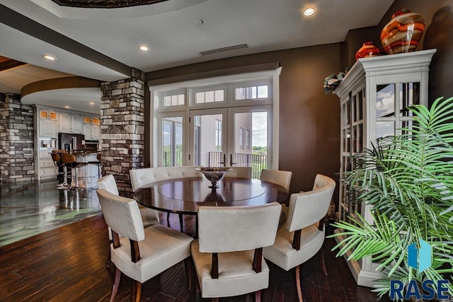 dining room featuring dark wood-type flooring and decorative columns