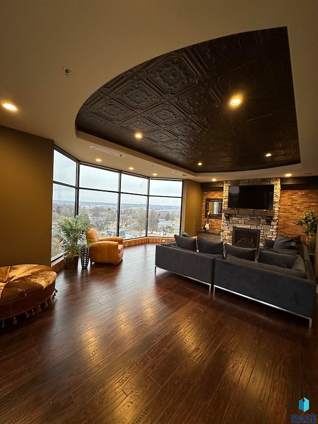 living room featuring a fireplace, dark wood-type flooring, and a tray ceiling