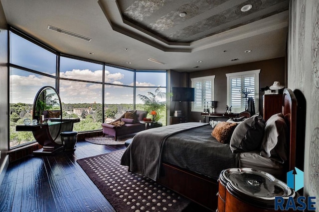 bedroom with a wall of windows, wood-type flooring, a tray ceiling, and multiple windows