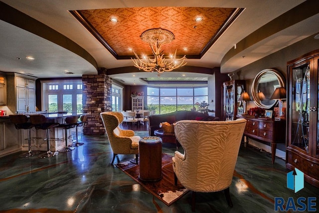 interior space featuring an inviting chandelier, a tray ceiling, and ornate columns