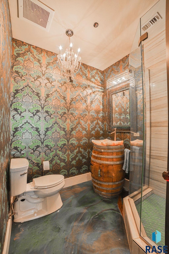 bathroom with an inviting chandelier, vanity, and toilet