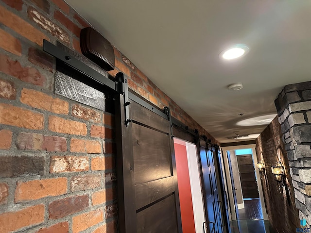 hallway with a barn door and brick wall