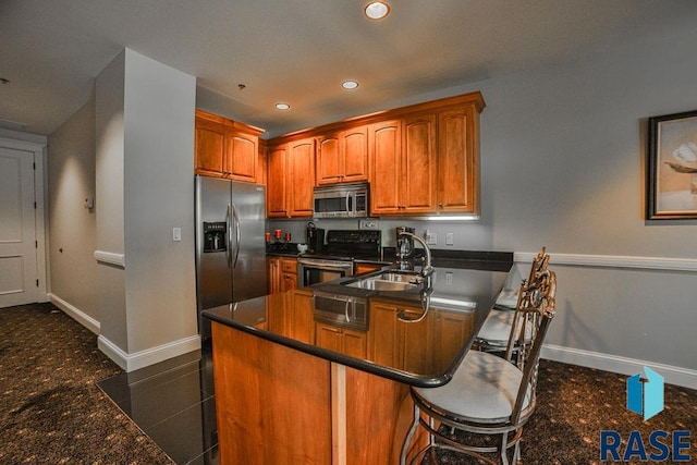 kitchen featuring kitchen peninsula, appliances with stainless steel finishes, dark tile patterned floors, and sink