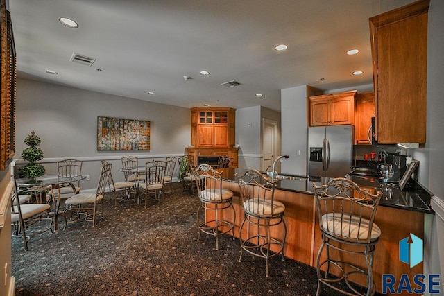 kitchen with sink, a kitchen bar, stainless steel fridge with ice dispenser, and a fireplace