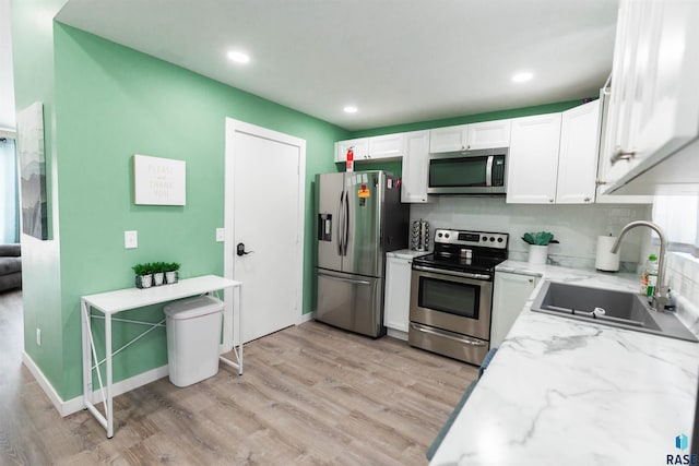 kitchen with stainless steel appliances, white cabinetry, light hardwood / wood-style floors, and sink