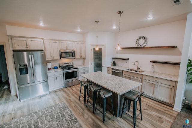 kitchen featuring a breakfast bar, stainless steel appliances, light wood-type flooring, and sink