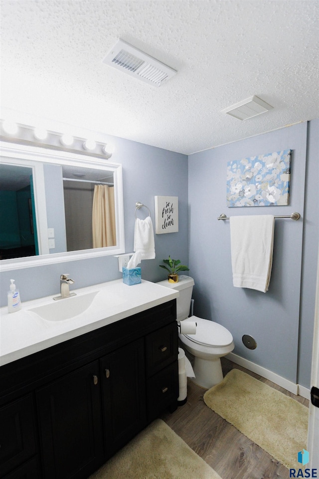 bathroom with vanity, wood-type flooring, a textured ceiling, and toilet