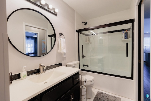 full bathroom with vanity, bath / shower combo with glass door, and toilet