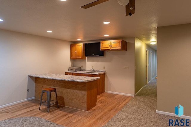 bar featuring light stone counters and light wood-type flooring