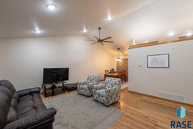 living room with ceiling fan, wood-type flooring, and vaulted ceiling