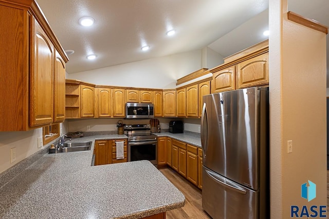 kitchen featuring sink, light hardwood / wood-style flooring, kitchen peninsula, lofted ceiling, and appliances with stainless steel finishes