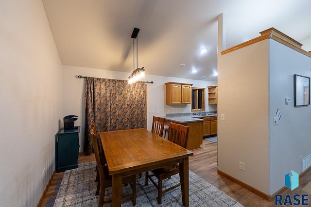 dining area featuring sink, lofted ceiling, and hardwood / wood-style flooring