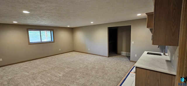 kitchen with light carpet, sink, and a textured ceiling