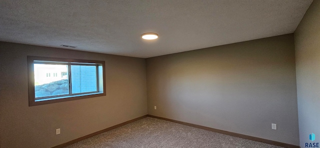 carpeted spare room with a textured ceiling