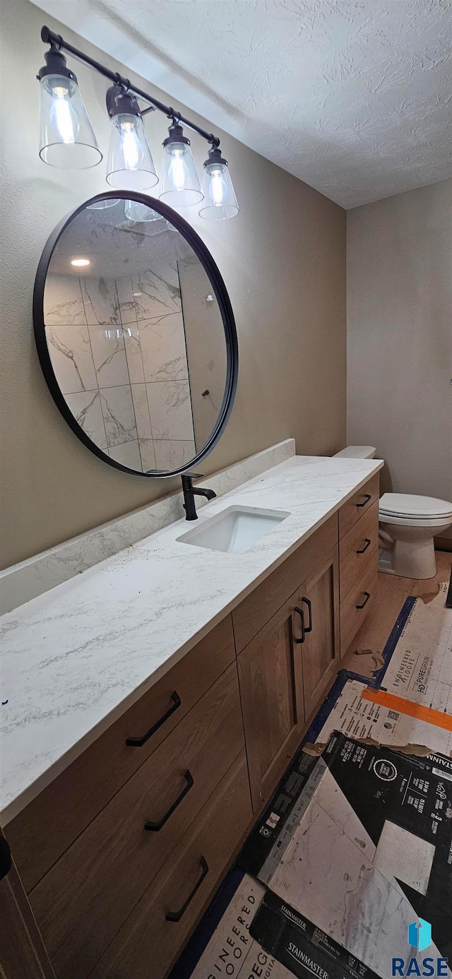 bathroom with vanity, toilet, and a textured ceiling