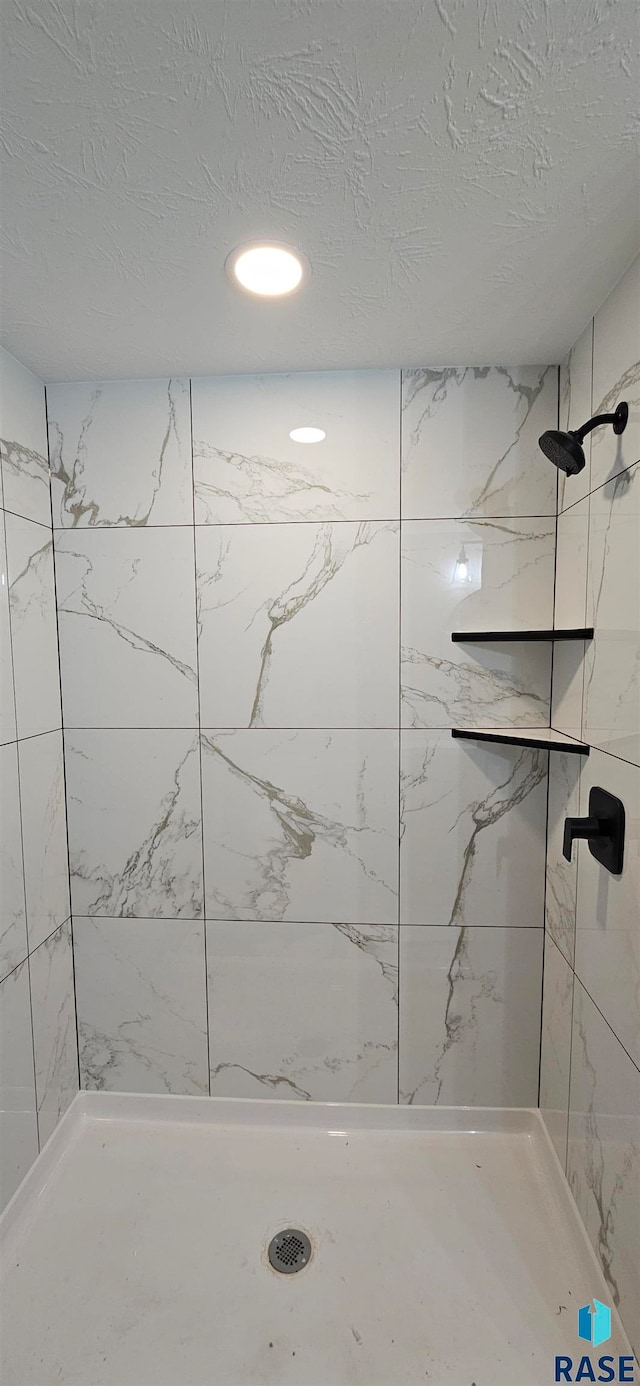 bathroom with a tile shower and a textured ceiling