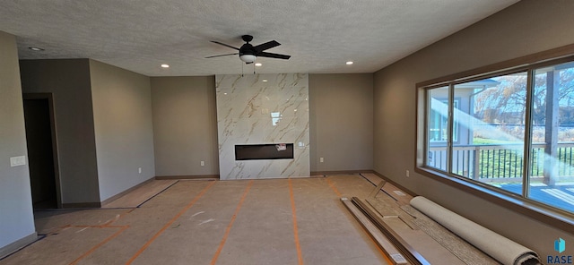 unfurnished living room featuring a fireplace, a textured ceiling, and ceiling fan