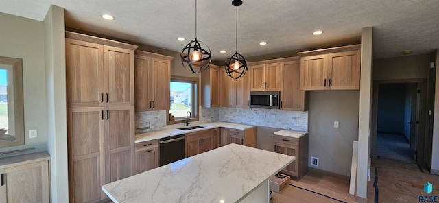 kitchen with light stone countertops, sink, a center island, backsplash, and appliances with stainless steel finishes