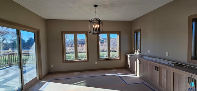 unfurnished dining area featuring a chandelier and a textured ceiling