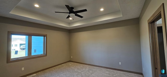 carpeted spare room with ceiling fan and a raised ceiling