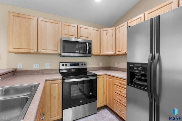 kitchen featuring light brown cabinets, sink, stainless steel appliances, lofted ceiling, and light tile patterned flooring