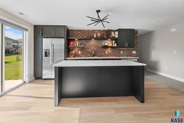 2704 S Snow Mass Ave, Sioux Falls, SD 57110 - kitchen with stainless steel fridge with ice dispenser, open shelves, baseboards, a center island, and plenty of natural light