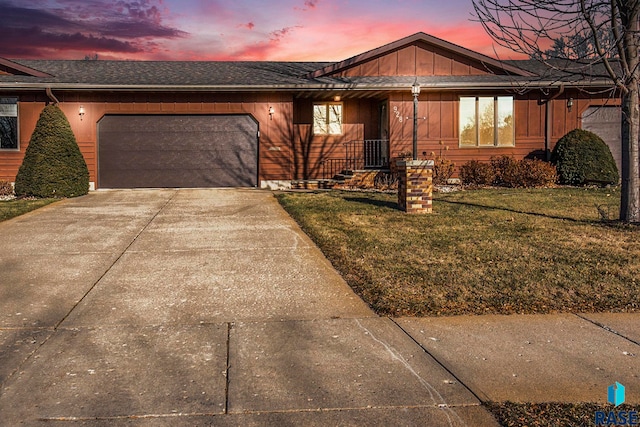 ranch-style home with a garage and a lawn