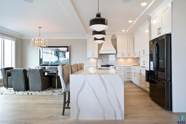 kitchen featuring white cabinetry, black refrigerator with ice dispenser, light hardwood / wood-style flooring, and custom range hood