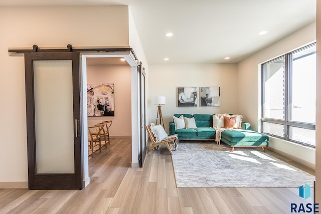 sitting room with a barn door and light hardwood / wood-style floors