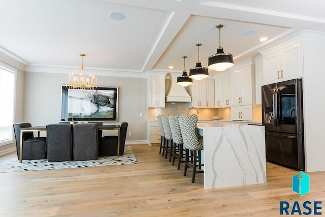 kitchen featuring white cabinetry, refrigerator with ice dispenser, decorative light fixtures, and light wood-type flooring