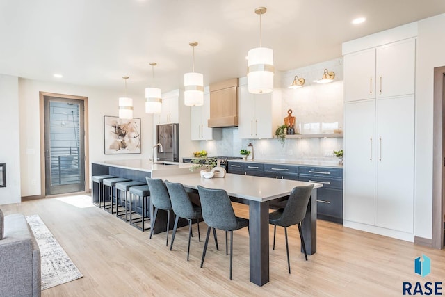 kitchen featuring pendant lighting, a breakfast bar, a center island with sink, and stainless steel refrigerator