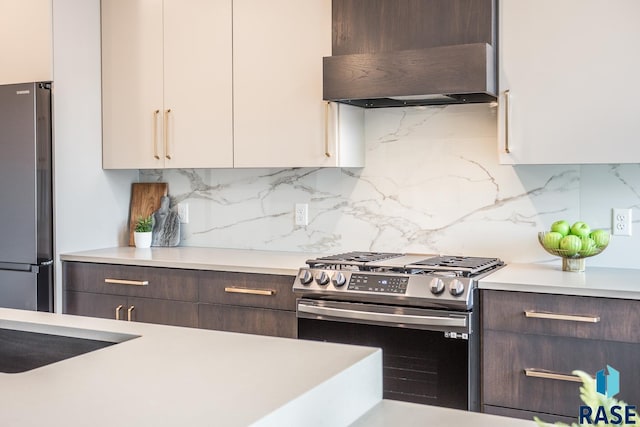 kitchen with range hood, backsplash, dark brown cabinets, white cabinets, and appliances with stainless steel finishes