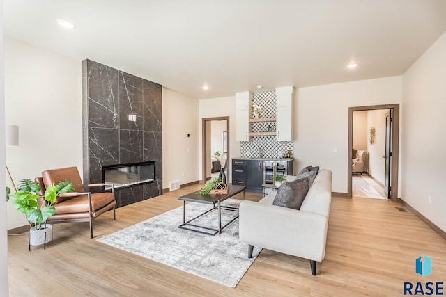 living room with bar, a premium fireplace, and light hardwood / wood-style floors