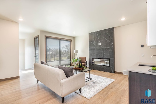 living room with sink, a tile fireplace, and light hardwood / wood-style flooring