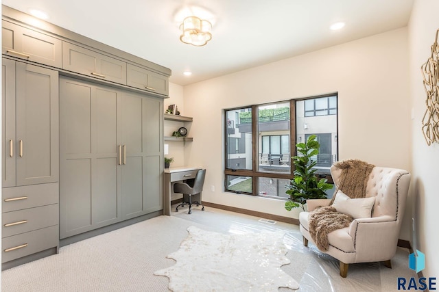 sitting room with light colored carpet and built in desk