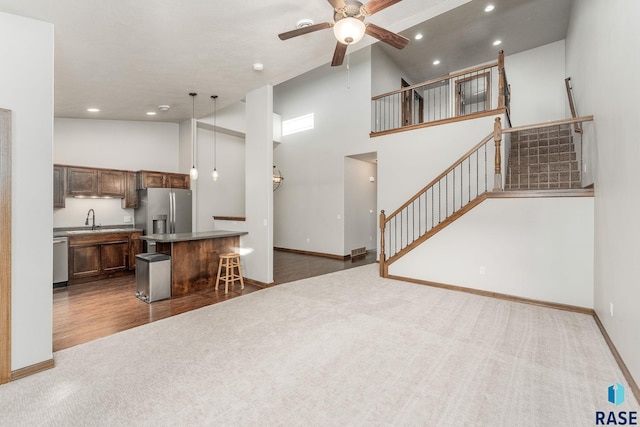 kitchen with a breakfast bar, high vaulted ceiling, hanging light fixtures, appliances with stainless steel finishes, and a kitchen island