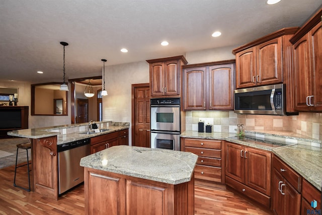 kitchen with appliances with stainless steel finishes, light hardwood / wood-style floors, and a kitchen island