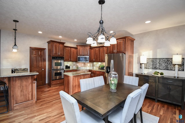 dining area with hardwood / wood-style flooring, sink, a textured ceiling, and a chandelier