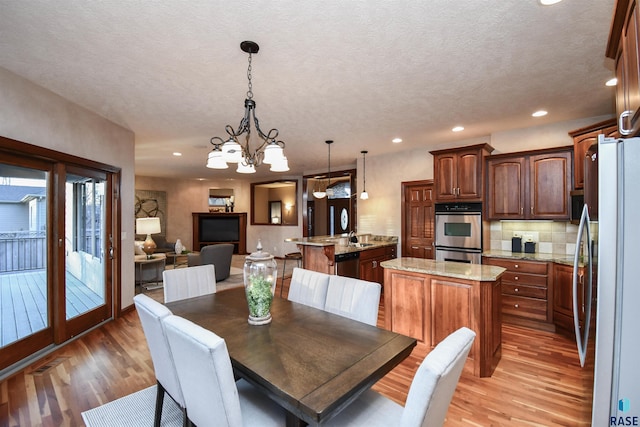 dining area featuring a chandelier, wood-type flooring, a textured ceiling, and sink