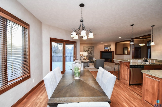 dining room with light hardwood / wood-style flooring, a wealth of natural light, a notable chandelier, and sink