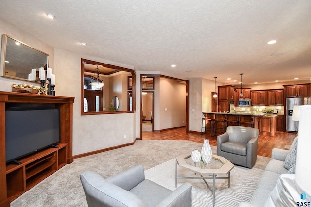 living room with crown molding, a textured ceiling, and light wood-type flooring